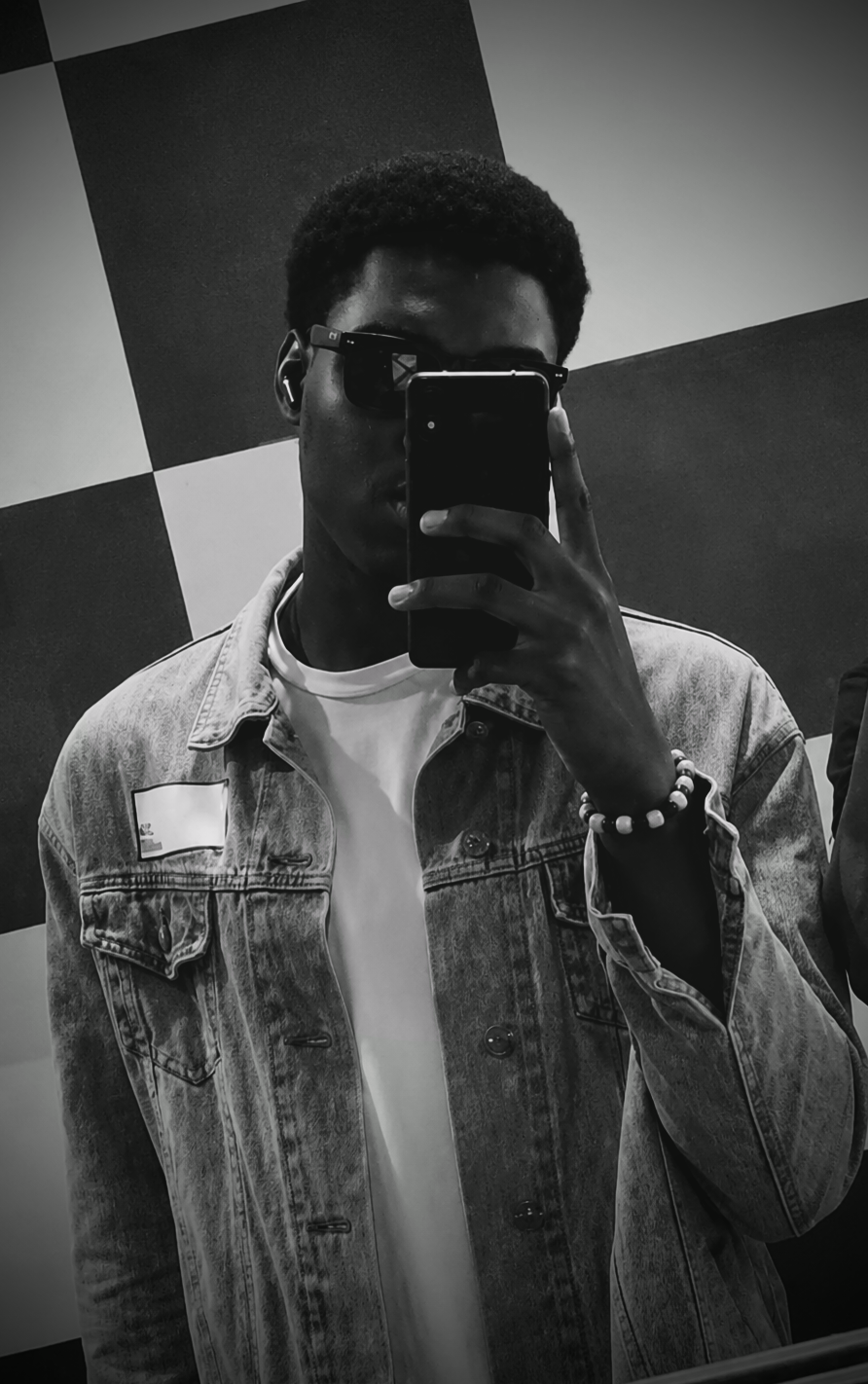 Divinne Amunega taking a mirror portrait in sunglasses and a denim jacket